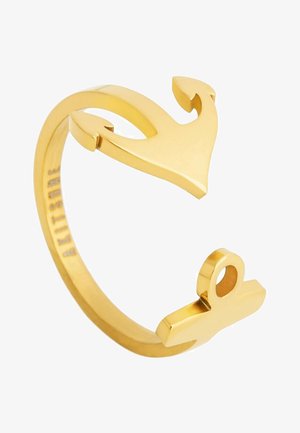 Arany színű gyűrű nyitott kialakítással, horgony formával és szív sziluettel. Sima felület, minimalista stílus, és gravírozott márkajelzés.