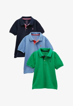 Trīs īsroku polo krekli — tumši zils ar rozā apdari, gaiši zils ar oranžu apdari un zaļš ar melnām pogām — sakārtoti pārklājoties.