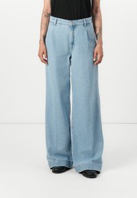 Pantalons en denim bleu clair à jambes larges avec une taille haute, dotés d'un bouton de fermeture et de lignes épurées. Le tissu a une texture lisse.