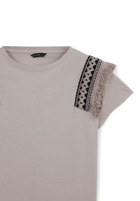 T-shirt gris clair avec des détails brodés noirs et des accents frangés sur les épaules, col rond et manches courtes.