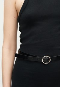 Μαύρο ριμπ αμάνικο τοπ με λαμπερή μαύρη ζώνη με ασημένια κυκλική αγκράφα στη μέση