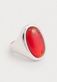 Inel din argint cu o piatră mare, ovală, roșie, cu o suprafață netedă și incluziuni subtile, montată într-un cadru lustruit.