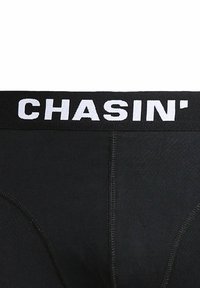 Mustad pesu valge vöökohaga, millel on tekst "CHASIN'" ja näha olevad õmbluse detailid kangal.