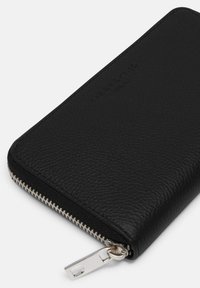 Schwarze Lederbrieftasche mit strukturiertem Finish, Reißverschluss und silberner Hardware. Markenname auf der Oberfläche geprägt. Kompakte rechteckige Form.