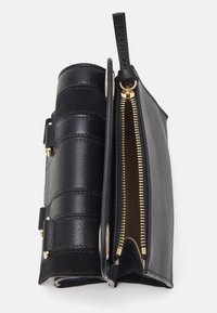Clutch bag in pelle nera con strisce testurizzate e accessori dorati. Caratterizzata da una chiusura con zip e una fodera interna liscia.