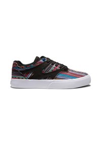 Zapatilla de lona negra con patrón de rayas multicolores, suela de goma blanca y ojete azul. Presenta texturas contrastantes y acentos de diseño.