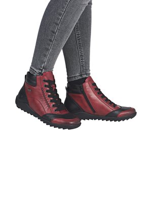 Czerwono-czarne buty typu high-top wykonane są ze skóry, mają teksturowaną powierzchnię, zapięcie na sznurowadła i zamek, a także solidną gumową podeszwę.