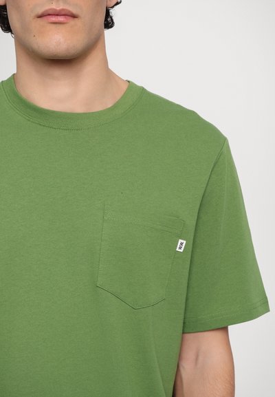 Green cotton T-shirt with a crew neck, short sleeves, and a chest pocket. Features a visible brand label on the pocket.