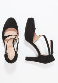 Chaussures à talons hauts en daim noir avec bout arrondi, brides autour de la cheville et un talon texturé pour plus de stabilité. Semelle intérieure plate.