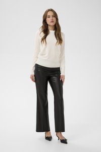 Ziloņkaula krāsas džemperis ar ribotu apakšmali, kombinēts ar augsta vidukļa, plašu melnu mākslīgās ādas biksēm un melniem smailiem papēžiem ar loku dekorāciju.