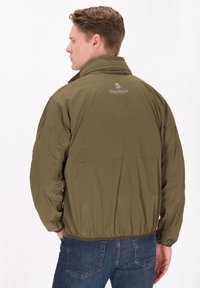 Jachetă de culoare verde măslinie, cu guler înalt, talie elastică și un logo pe spate. Textură netedă și material ușor.