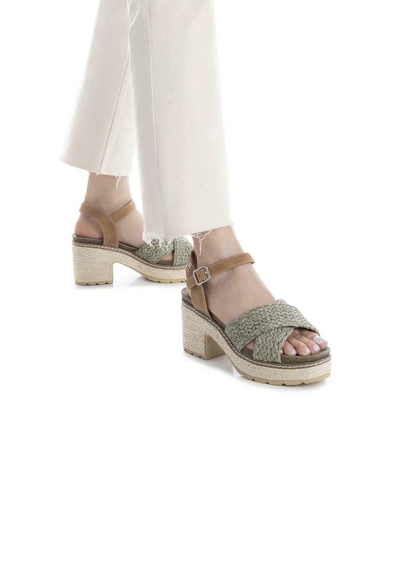 Sandalias de cuña con parte superior de tejido verde, correa de tobillo en color marrón claro y suela plataforma texturizada en beige. Diseño de punta abierta con un tacón robusto.
