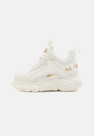 Chunky white sneakers featuring a textured faux leather upper, gold accents, and a thick, cushioned rubber sole with a distinctive shape.