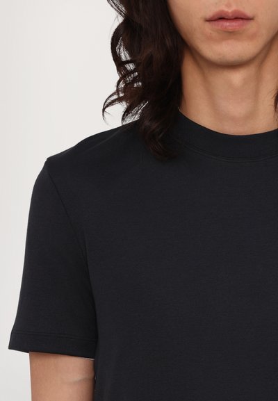 Svart kortermet t-skjorte med rund hals, laget av glatt stoff. Har en subtil tekstur og avslappet passform, uten ekstra mønstre.