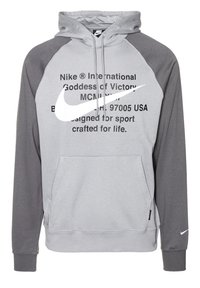 Grå huvtröja med mörkgrå raglanärmar, framficka i kengurustil, framträdande vitt Nike-logotyp och tryckt text på bröstet.