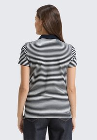 Marineblå og hvid stribet polo skjorte med marineblå krave, korte ærmer og en tætsiddende pasform. Stof i bomuldsblanding med ribbet tekstur.