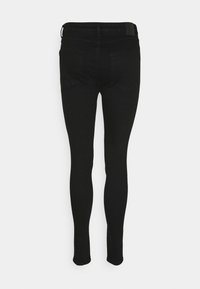 Jeans negros ajustados con una textura de denim suave, que cuentan con una cintura de altura media y bolsillos traseros. Diseño limpio sin adornos visibles.