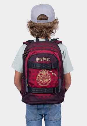 Zaino a quadri rosso e nero con logo e stemma dorati "Harry Potter", spallacci regolabili e tasche laterali.