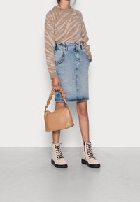 Beżowy sweter w paski, dżinsowa spódnica ołówkowa, beżowa torebka typu slouchy, jasne botki z czarnymi sznurówkami, teksturowany materiał i dopasowany fason.