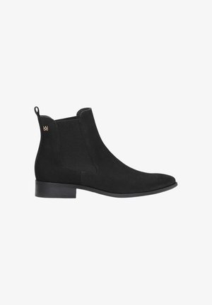 Bottine en suède noire avec des panneaux élastiques sur les côtés, bout rond et un petit talon carré. Elle présente une languette à l'arrière et un subtil accent de logo.