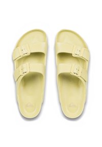 Gule rutsche-sandaler med to justerbare spænder. Lavet af glat, skinnende materiale med en kontureret fodseng. Diskret logo prægede på sålen.
