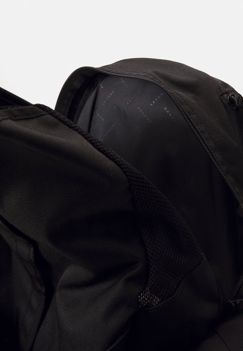 Black backpack with a textured fabric, featuring a zipper closure and mesh pocket inside. The inner lining has a subtle printed logo pattern.