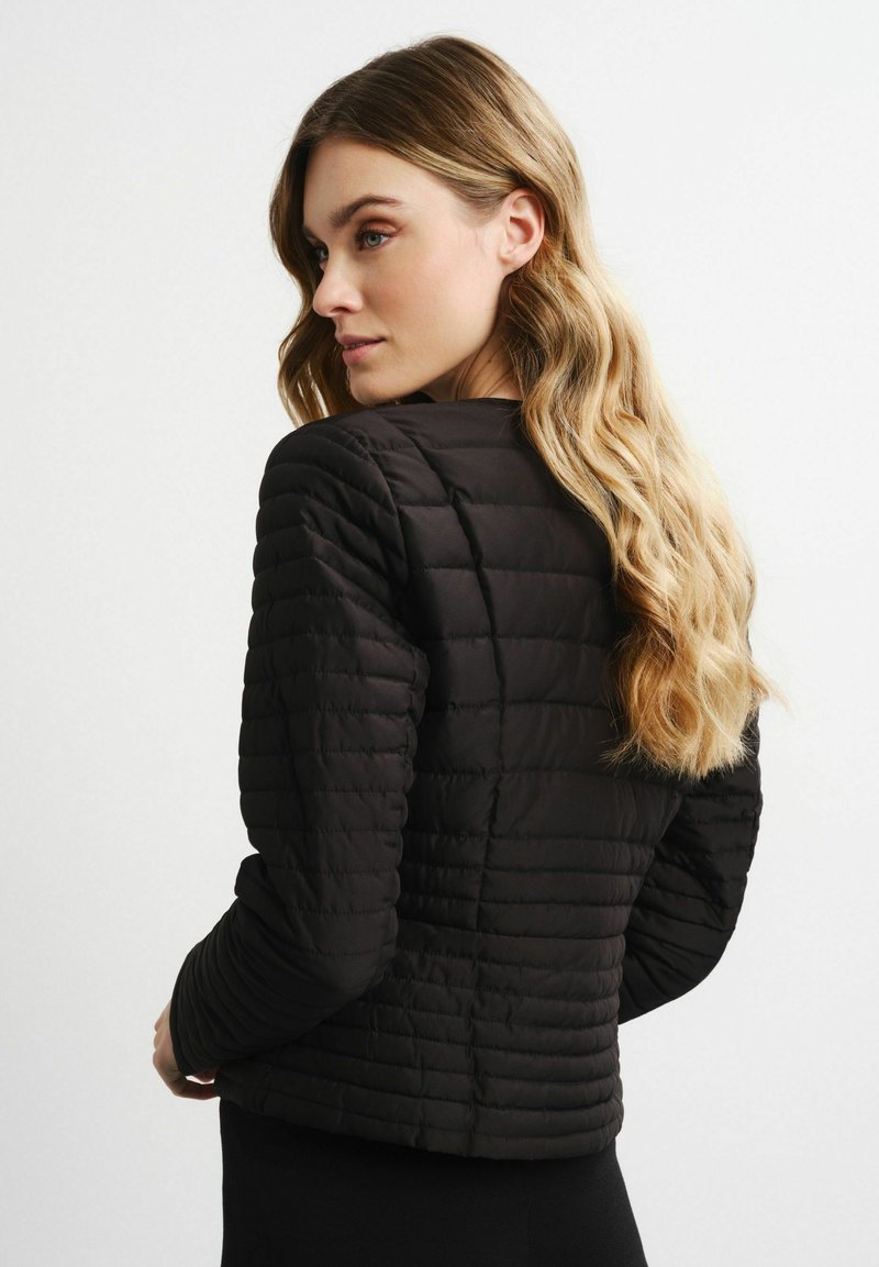 Schwarze Puffy-Jacke mit horizontaler Steppung, taillierter Passform und hohem Kragen. Lange Ärmel und glatte, leicht glänzende Oberfläche.