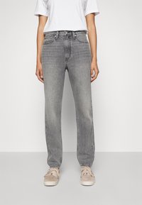 Grijze high-waisted jeans met een rechte pijp, vijf zakken en subtiele vervaging. Gecombineerd met beige vetersneakers en een wit T-shirt.