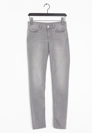 Jeans skinny grigi chiaro con tasche anteriori e posteriori, passanti per cintura e chiusura con bottone, appesi a una gruccia di plastica nera.