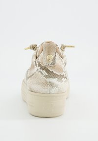 Zapatilla deportiva con estampado de serpiente en beige, suela gruesa, cordones con puntas doradas atados en nudos y botón dorado de marca en la lengüeta del talón.