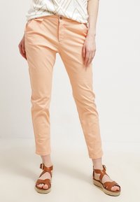 Różowe, krótkie spodnie o dopasowanym kroju, z przednimi kieszeniami i zapięciem na guzik. Połączone z brązowymi sandałami na paski.