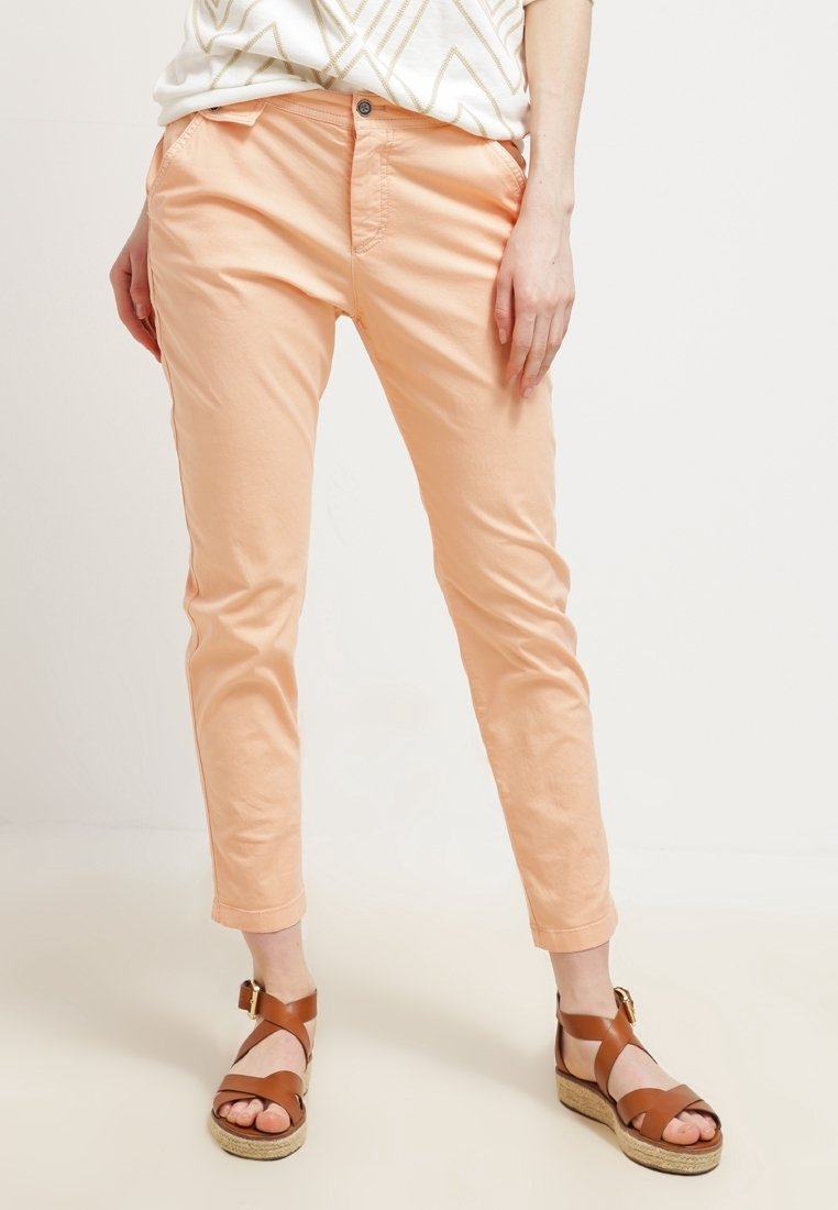 Różowe, krótkie spodnie o dopasowanym kroju, z przednimi kieszeniami i zapięciem na guzik. Połączone z brązowymi sandałami na paski.