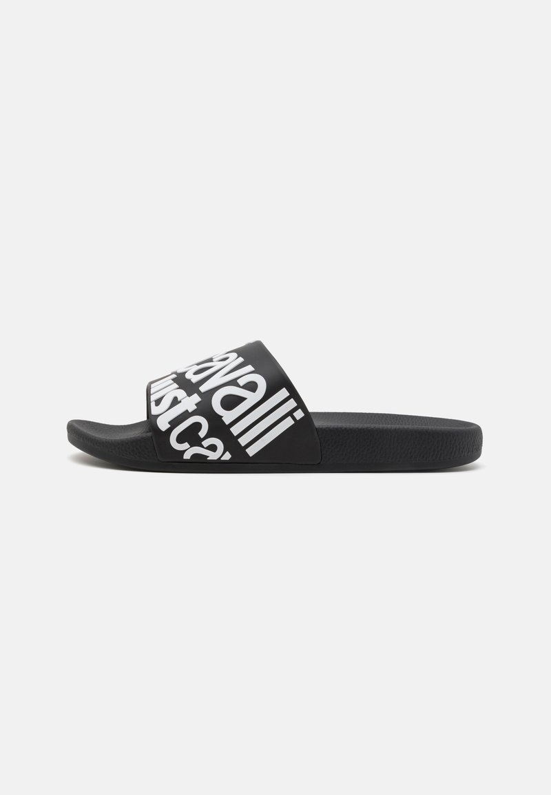 Black slide sandal with a wide strap featuring white text and a textured footbed. The sole is flat and made of flexible material.