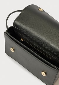 Mala de mão em pele preta texturizada com aba e ferragens douradas. Possui um bolso com fecho de correr no interior e fecho de pressão. Design compacto.