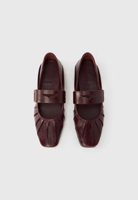 Μπαλαρίνες από δέρμα μπορντό με τετράγωνη μύτη, διαθέτουν ευρύ λουράκι στο πάνω μέρος και πιετέ σχέδιο για υφή. Λείος εσωτερικός επένδυση.