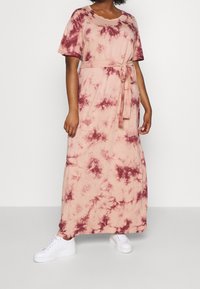 Maxi-mekko pehmeästä kankaasta, jossa on solmittava vyö, lyhyet hihat ja vaaleanpunainen marmori-kuvio burgundi-väreissä. Yhdistettynä valkoisiin lenkkareihin.