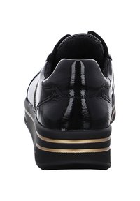 Schwarze Lackledersneaker mit abgerundeter Form, goldenen Akzenten an der Mittelsohle und strukturiertem schwarzen Gummi-Außensohle. Minimale sichtbare Nähte.