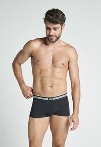 Svarta boxertrosor med en mjuk, elastisk midjeband med dubbla vita ränder. Tillverkade av stretchigt material, designade för komfort och passform.