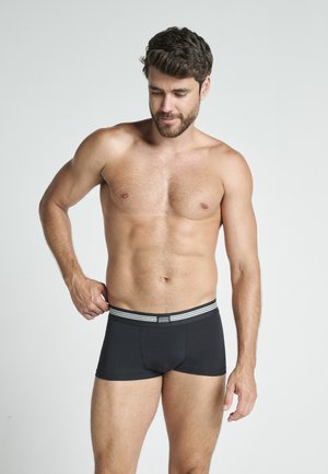 Boxer briefs negros con una suave cinturilla elástica que presenta dos franjas blancas. Fabricados con un tejido elástico, diseñados para la comodidad y el ajuste.