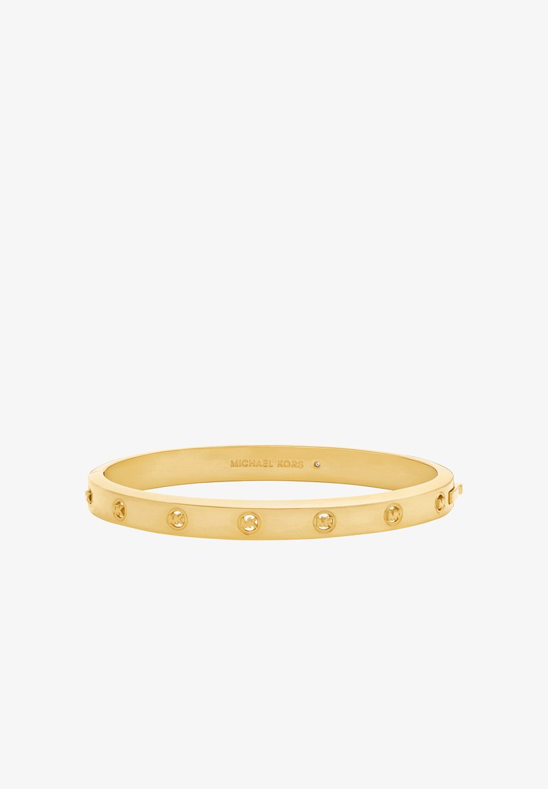 Bracelet jonc en ton or avec une finition lisse et des découpes circulaires, gravé d'un logo à l'intérieur et orné de cristaux ronds.