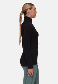 Top fitted nero a maniche lunghe con colletto alto, realizzato in un tessuto testurizzato e con un piccolo logo sul petto. Abbinato a leggings verde chiaro.
