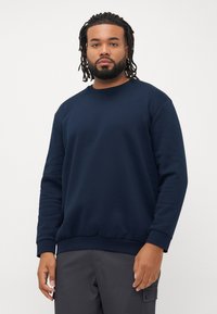 Navyblaue sweatshirt aus weichem Stoff mit Rundhalsausschnitt, gerippten Bündchen und Saum. Besitzt einen lockeren Schnitt und ein minimalistisches Design.