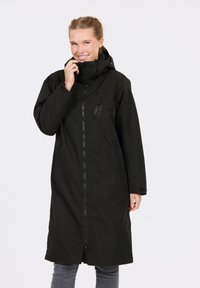 Black waterproof long coat with a zip front, high collar, and adjustable hood. Features a side zip pocket and relaxed fit. Soft, smooth texture.