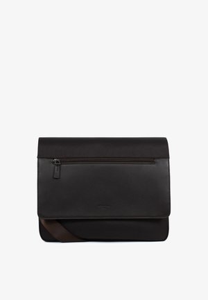 Czarna torba listonoszka z przednią kieszenią na suwak, zamknięciem na klapę oraz regulowanym brązowym paskiem na ramię, wykonana ze skóry i tkaniny.