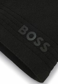 Black knit beanie with textured fabric, featuring a prominent black logo "BOSS" sewn on the front and ribbed design on the band.