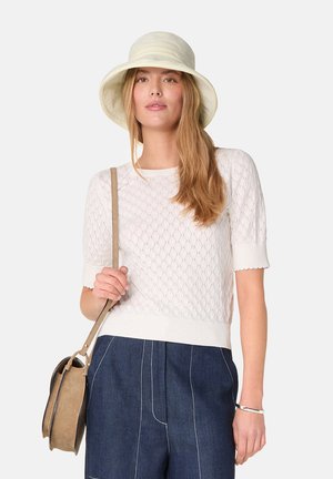 Haut tricoté blanc à manches courtes avec un motif en losanges, associé à un pantalon en denim taille haute et un sac à bandoulière beige. Chapeau à larges bords.