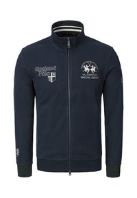 Mörkblå zip-up jacka i fleece, med broderade logotyper och randig krage. Ribbstickade muddar med gröna och blå accenter.