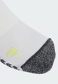 Biała skarpetka z szarym palcem i piętą, z żółtym logo i textured materiałem. Projekt zawiera czarno-białe akcenty w wzory.