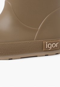 Botín de goma marrón hasta el tobillo con un upper liso, suela texturada y un logo "igor" embossado en el lado. Diseño redondeado sin patrones visibles.