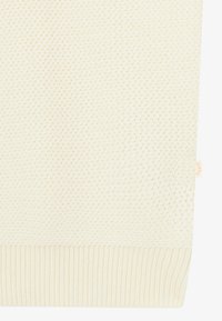 Lyscremefarvet strikket sweater med et struktureret mønster, der har en ribbet kant og et lille mærke på siden.